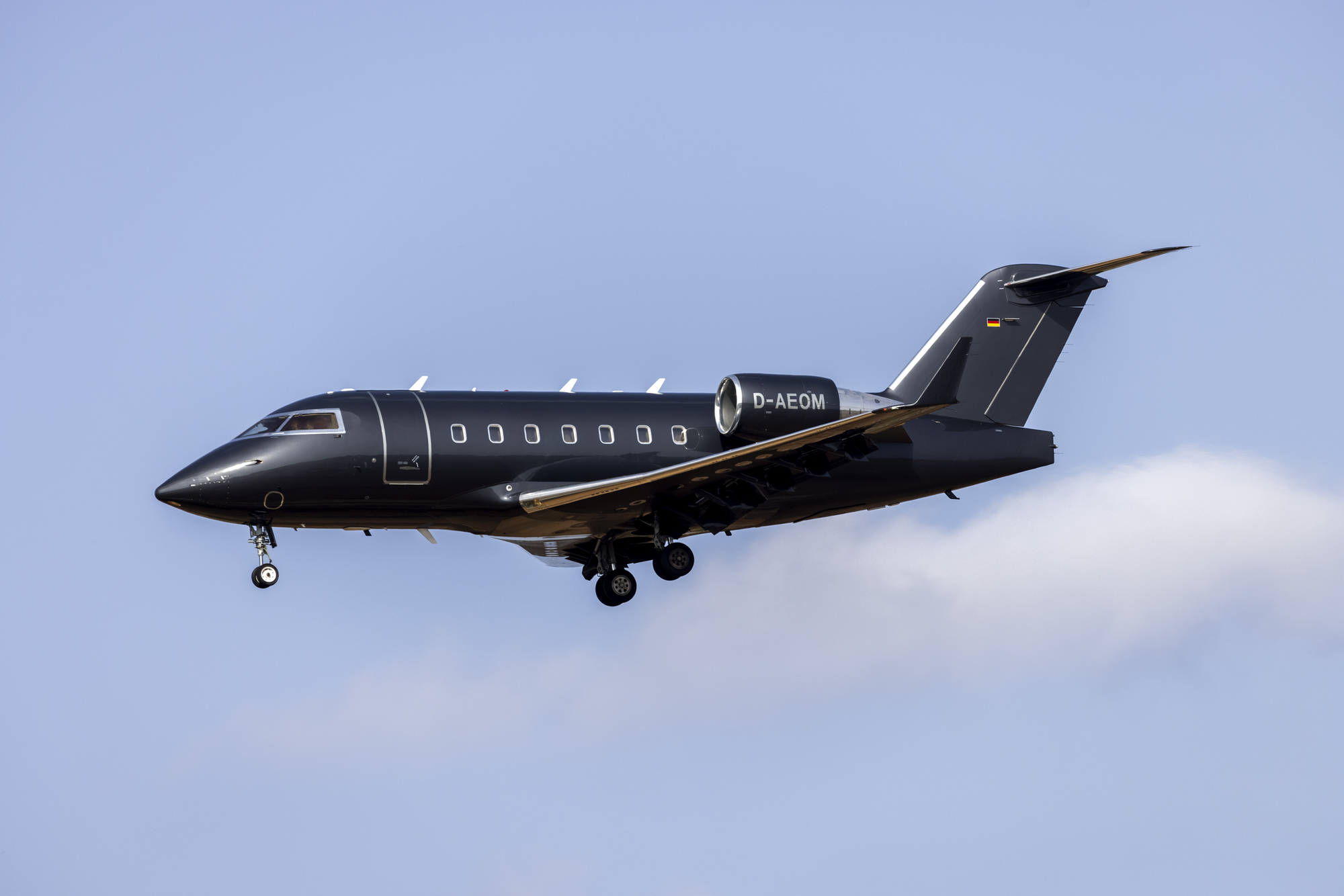  A black Challenger 604 private jet descending to an airport