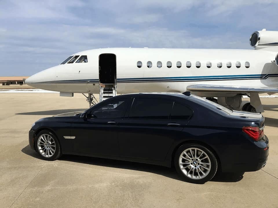 A car parked on the ramp next to a private jet