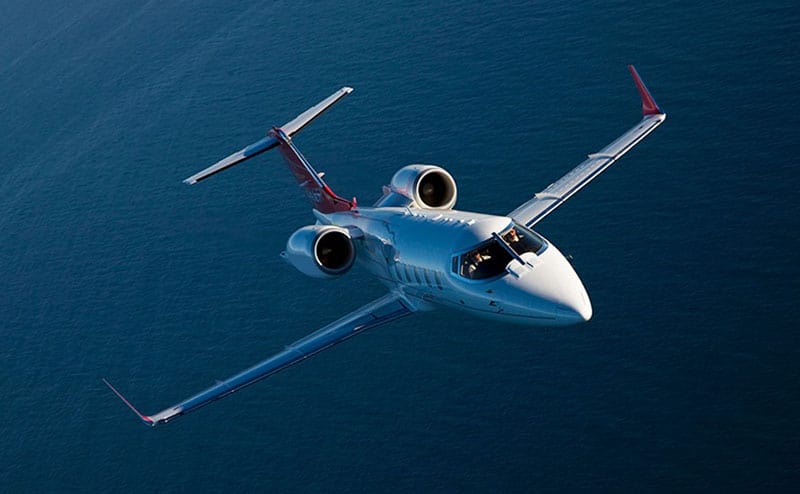 A Learjet 60XR private jet flying through the air above the sea