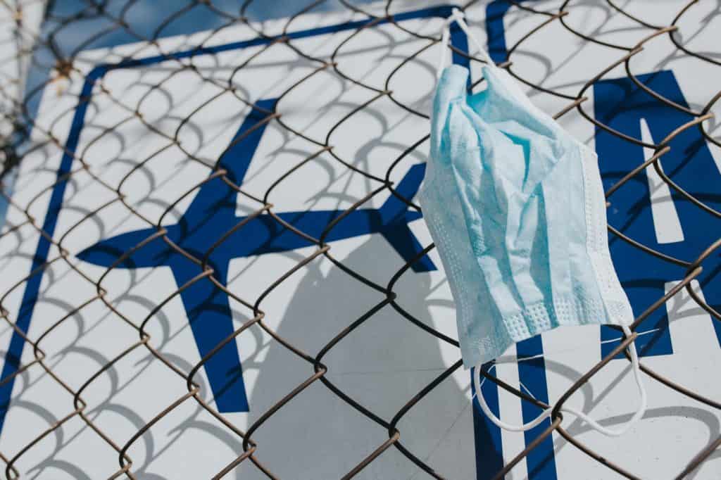 a doctor's mask hanging on the fence at an airport