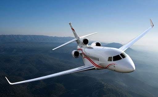 Falcon 7X private jet flying over mountains 