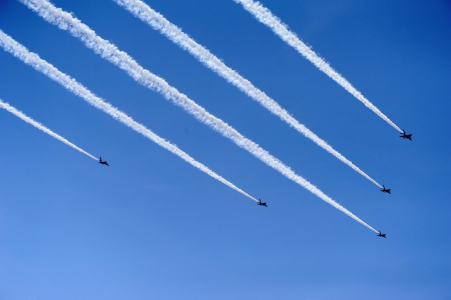 five military planes flying through the sky leaving contrail